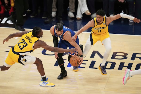 New York Knicks guard Josh Hart, middle, is defended by Indiana Pacers forward Aaron Nesmith (23) and guard Tyrese Haliburton (0) during the first half of Game 3 of the Eastern Conference finals of the NBA basketball playoffs Sunday, May 25, 2025, in Indianapolis. (AP Photo/Jeff Roberson)