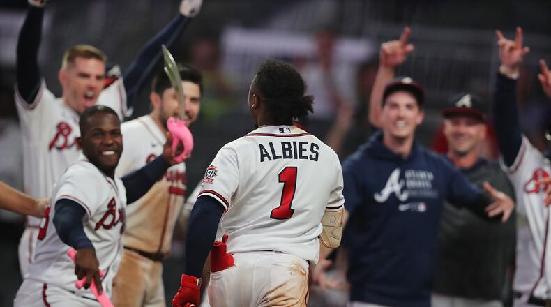 081121 Atlanta: —WALK OFF HOMER —Atlanta Braves players await second baseman Ozzie Albies at home plate on his 3-run walk off homer for a 8-6 victory over the Cincinnati Reds during the 11th inning of a MLB baseball game on Wednesday, August 11, 2021, in Atlanta.   “Curtis Compton / Curtis.Compton@ajc.com”