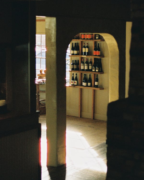 A farmhouse style shop with a view of wine shelves through a door.