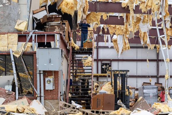 William Fraser takes a photograph in the warehouse of the damaged building of Specialty Distributors after a tornado passed through an industrial industrial park on Thursday, April 3, 2025, in Jeffersontown, Ky. (AP Photo/Jon Cherry)
