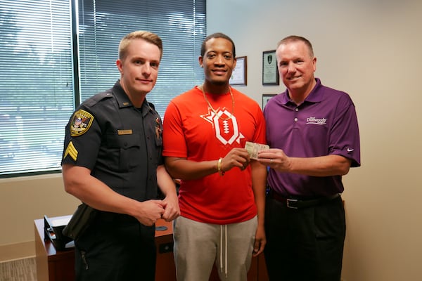 Randrell Lewis (center) poses with Dunwoody police Sgt. Robert Parsons (left) and Chief Billy Grogan after Lewis returned $2,100 he took from an armored truck spill on I-285.