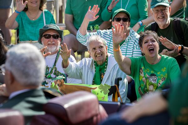 Celebrating her 88th birthday, Mimi Rissman (center) is flanked by family members Sean Beebe (left) and Marie Beebe (right) as they wave at dignitaries during the 200th anniversary of Savannah's first St. Patrick's Day parade, Saturday, March 16, 2024, in Savannah.  (Stephen B. Morton for the AJC)