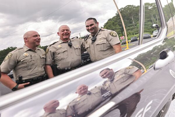 Capt. Chuck Smith (center) enjoys a moment with his sons, Parker (left) and Kyle, who are deputies for the Coweta County Sheriff's Office. (Natrice Miller/AJC)