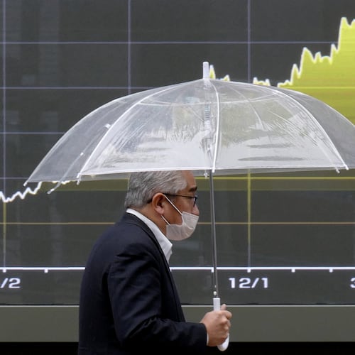 A person walks in front of an electronic stock board showing Japan's Nikkei index chart at a securities firm Monday, March 23, 2026, in Tokyo. (AP Photo/Eugene Hoshiko)