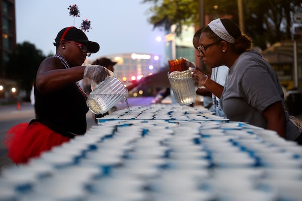 Volunteers with Norfolk Southern Railway fill cups with water at a water station along "Cardiac Hill" during the 56th running of the Atlanta Journal-Constitution Peachtree Road Race in Atlanta on Friday, July 4, 2025. (Abbey Cutrer/AJC)
