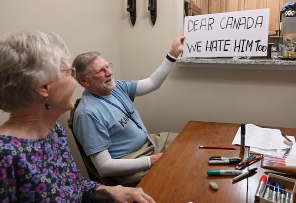Peggy Smith (left) checks out Fowler Bush's sign ahead of a protest in Stone Mountain. “I totally trusted our government growing up in the 1950s and ’60s, even when I maybe shouldn’t have, but I don’t think anyone does now,” she said. (Hyosub Shin/AJC)