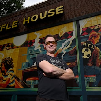 Artist Nick Benson poses for a portrait in front of his mural, commissioned by Downtown Atlanta Inc., near Centennial Park, on Thursday, May 21, 2026, in Atlanta. Benson created the work as an Atlanta homage to Edward Hopper’s iconic painting "Nighthawks." (Hyosub Shin/AJC)