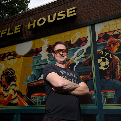 Artist Nick Benson poses for a portrait in front of his mural, commissioned by Downtown Atlanta Inc., near Centennial Park, on Thursday, May 21, 2026, in Atlanta. Benson created the work as an Atlanta homage to Edward Hopper’s iconic painting "Nighthawks." (Hyosub Shin/AJC)