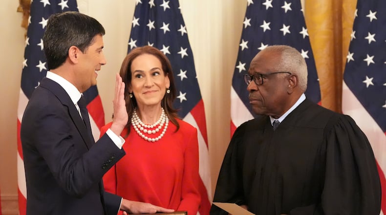 Justice Clarence Thomas, right, administers the oath during the swearing in of Kevin Warsh as Chairman of the Federal Reserve, left, as Warsh's wife Jane Lauder looks on, in the East Room of the White House, Friday, May 22, 2026, in Washington. (AP Photo/Alex Brandon)