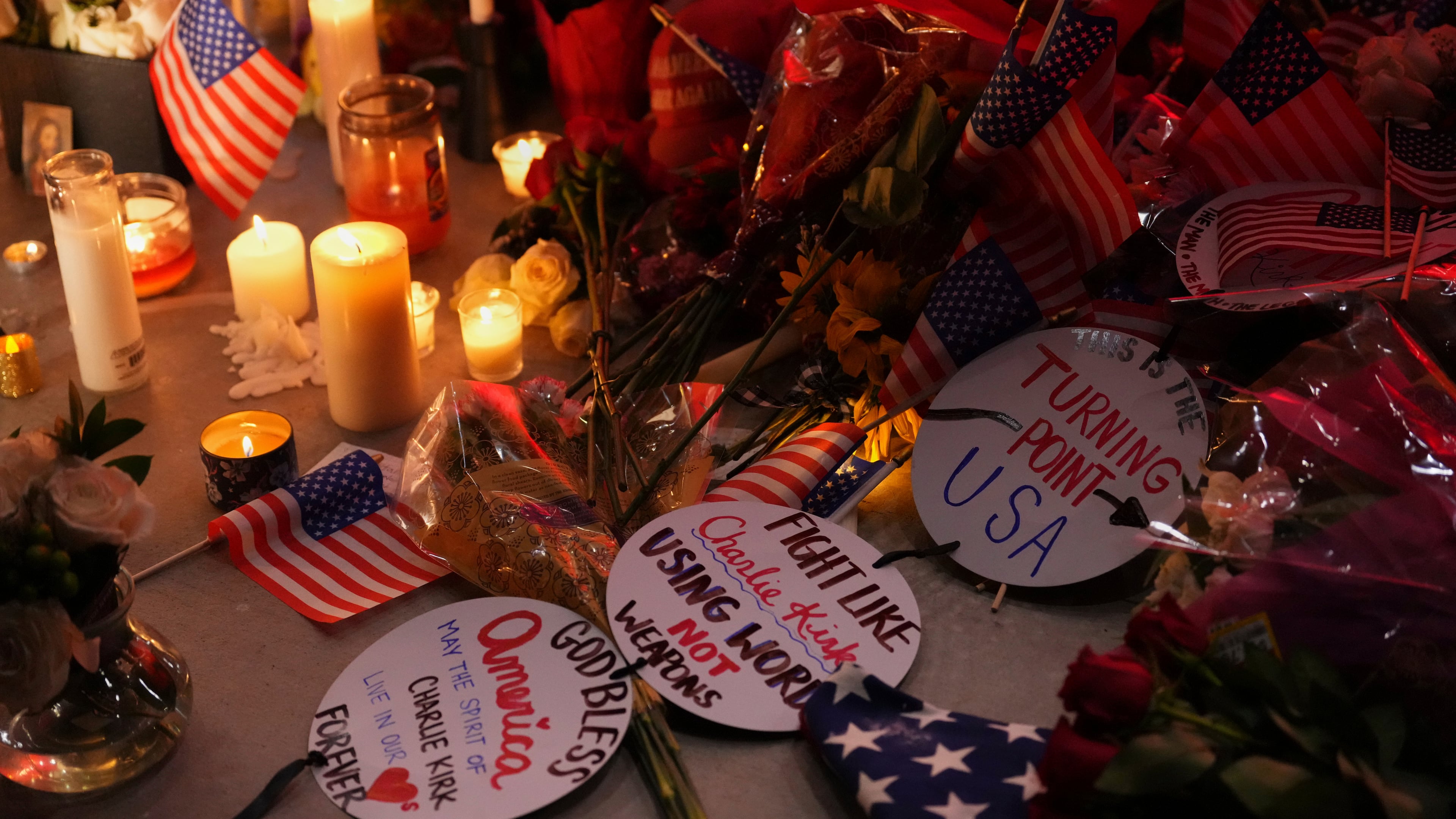 Flags, candles and signs sit at a vigil for Charlie Kirk, the CEO and co-founder of Turning Point USA who was shot and killed, Thursday, Sept. 11, 2025, in Orem, Utah. (AP Photo/Lindsey Wasson)