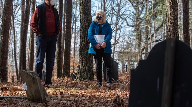 Johns Creek's Historical Society president Joan Compton (R) and board member Kirk Canaday look over a headstone at the Macedonia Cemetery during a visit in 2021. STEVE SCHAEFER FOR THE ATLANTA JOURNAL-CONSTITUTION