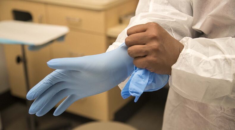 Kay Hayes, American Family Care-Buckhead office manager, places gloves on during a mock coronavirus training at the American Family Care located inside the Piedmont West Outpatient Center in Atlanta, Tuesday, March 3, 2020. (ALYSSA POINTER/ALYSSA.POINTER@AJC.COM)
