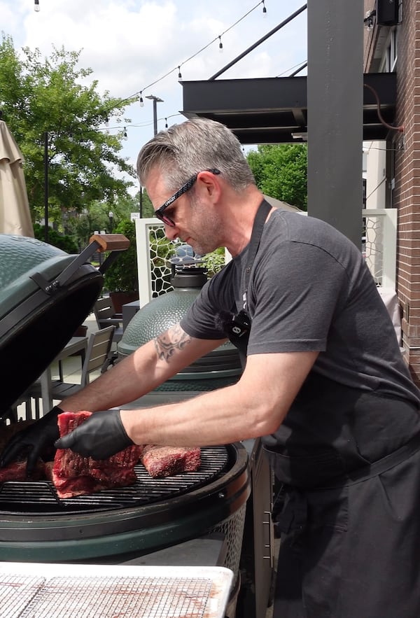 Man cooking meat on an outdoor grill.
