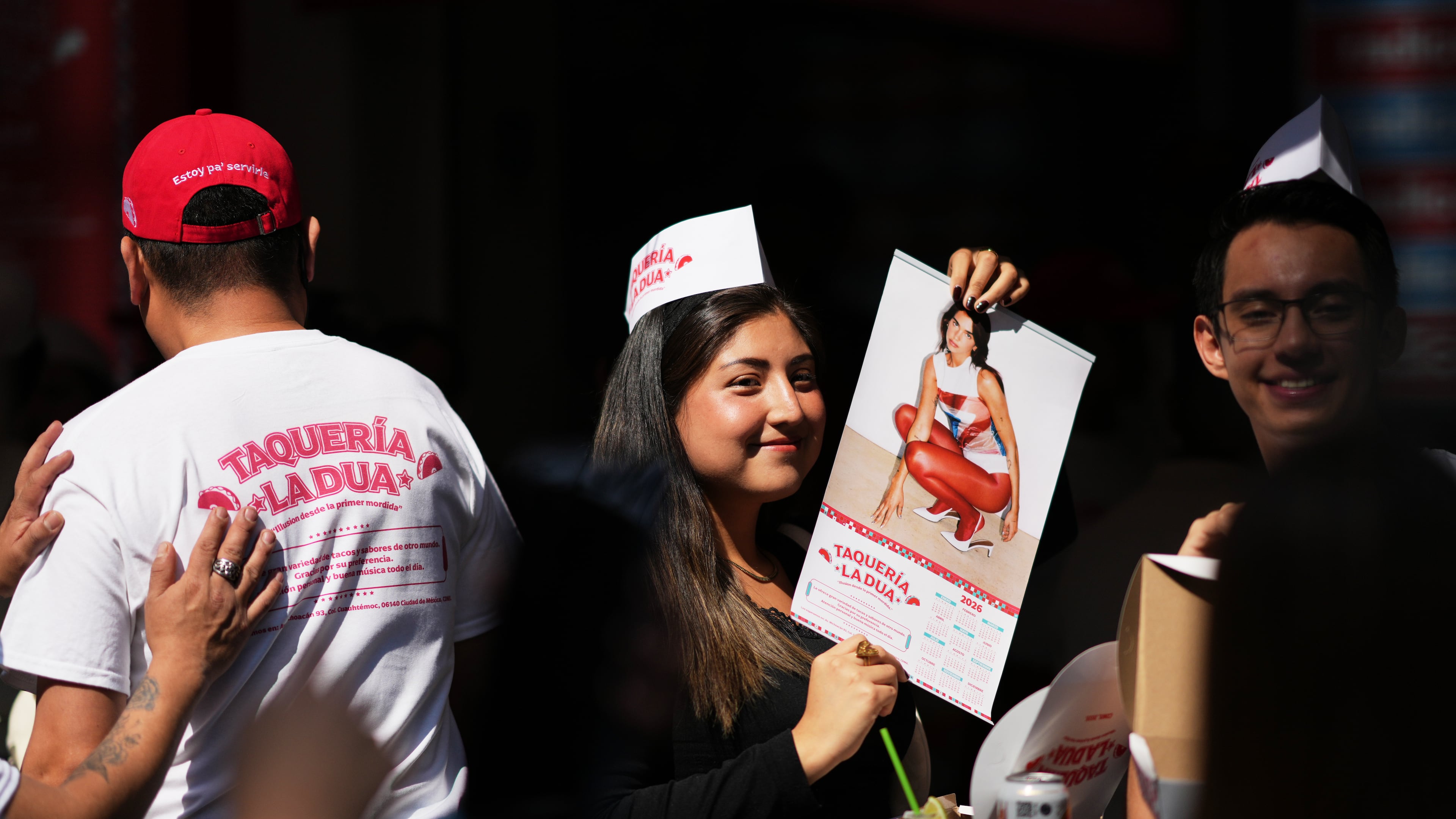 A consumer holds up a Dua Lipa calendar during the opening of the music star's taqueria, a pop-up restaurant for her fans in Mexico City, Monday, Dec. 1, 2025. (AP Photo/Eduardo Verdugo)