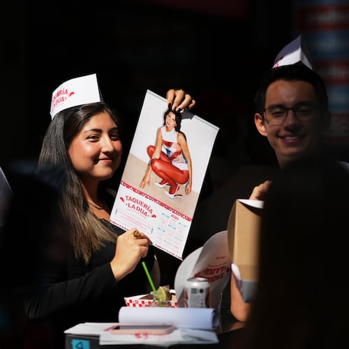 A consumer holds up a Dua Lipa calendar during the opening of the music star's taqueria, a pop-up restaurant for her fans in Mexico City, Monday, Dec. 1, 2025. (AP Photo/Eduardo Verdugo)