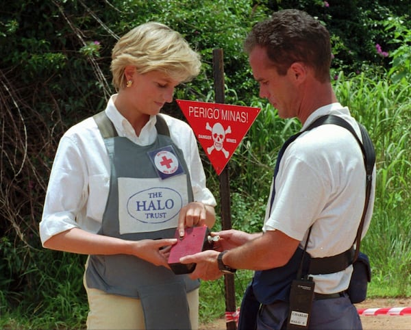 FILE - Diana, Princess of Wales, left, uses a remote switch to trigger the detonation of some explosive ordinance dug up by mine sweepers in Huambo, central Angola, Jan. 15, 1997. (AP Photo/Giovanni Diffidenti, File)