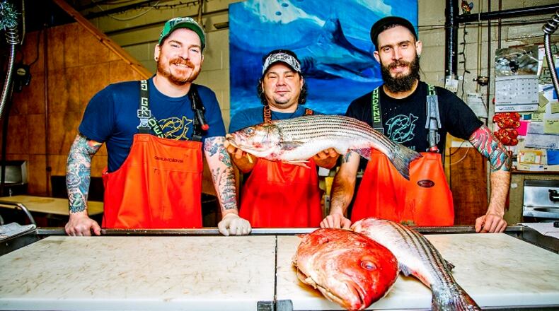 Tim Reynolds, senior fishmonger, Henry Dewey, owner, and Kyle Houghtelin, fishmonger, pose for a portrait behind the counter at Penn Avenue Fish Company in the Strip District. (Andrew Rush/Pittsburgh Post-Gazette/TNS)