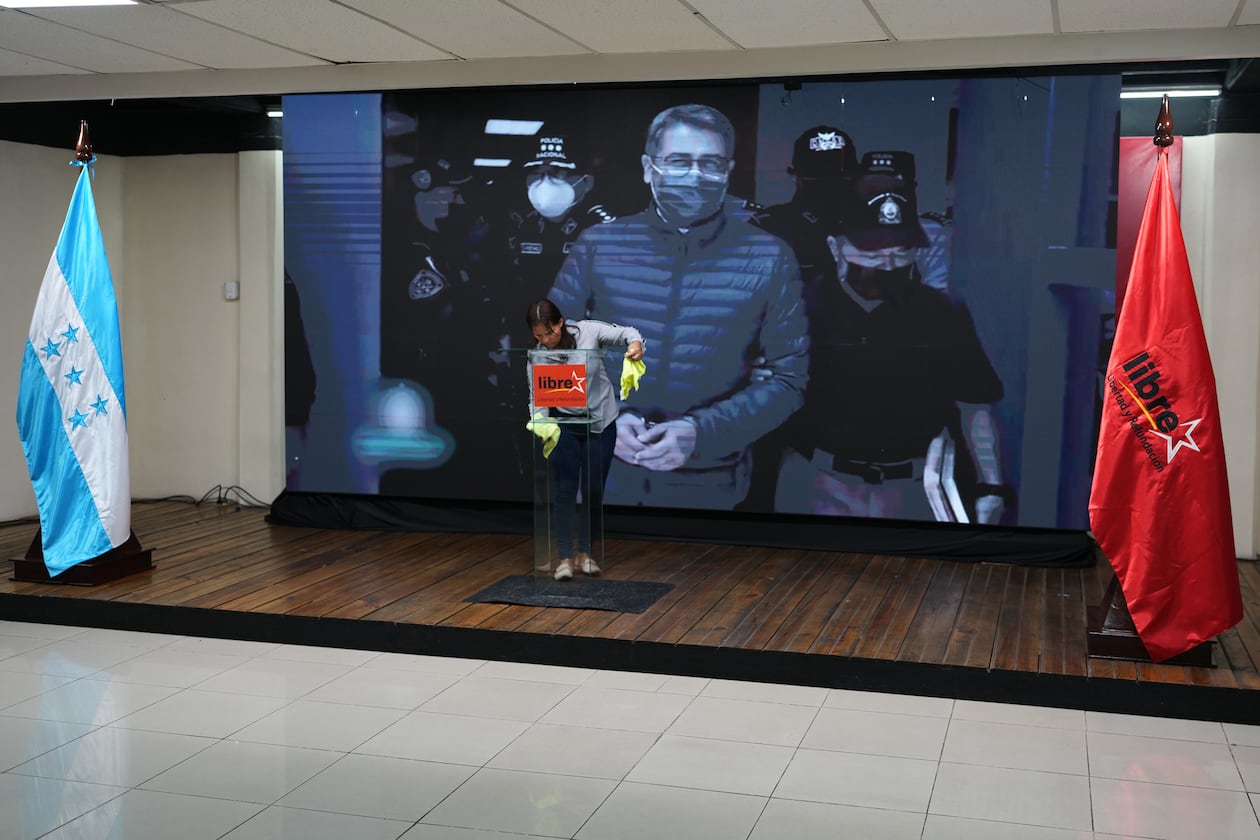 A screen displays an image of former Honduran President Juan Orlando Hernandez, a day after President Donald Trump said he plans to pardon Hernandez for a 2024 drug trafficking sentence, before the start of a press conference of Ruling party presidential candidate Rixi Moncada in Tegucigalpa, Honduras, Saturday, Nov. 29, 2025. (AP Photo/Moises Castillo)