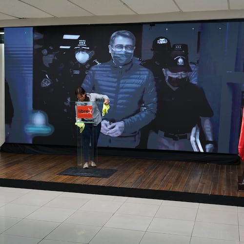 A screen displays an image of former Honduran President Juan Orlando Hernandez, a day after President Donald Trump said he plans to pardon Hernandez for a 2024 drug trafficking sentence, before the start of a press conference of Ruling party presidential candidate Rixi Moncada in Tegucigalpa, Honduras, Saturday, Nov. 29, 2025. (AP Photo/Moises Castillo)