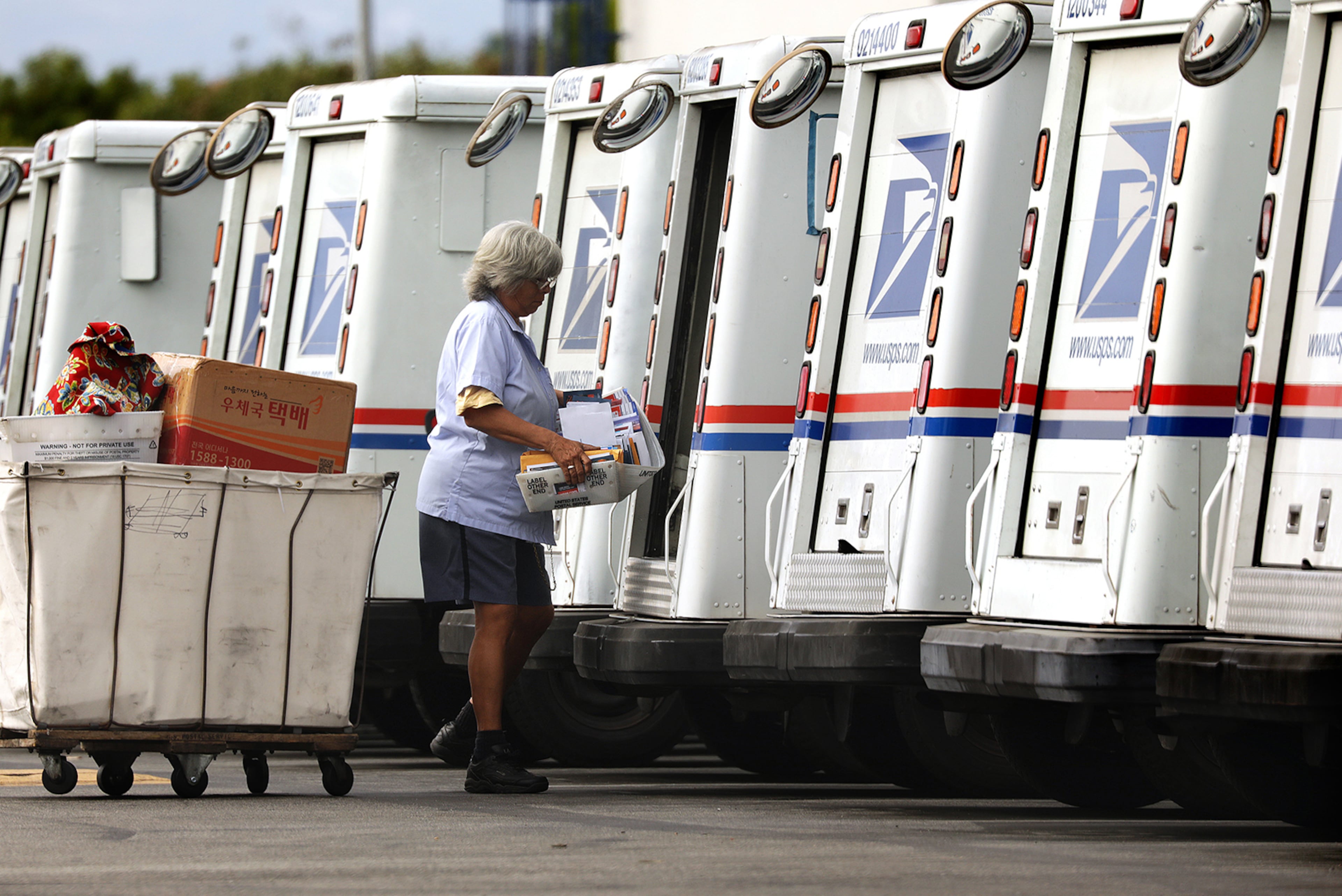 A USPS worker loads a truck for mail delivery.