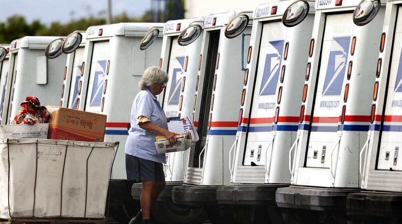A mail carrier loads a truck for delivery. (FILE)