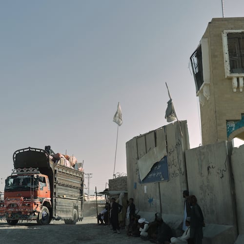 People wait near the closed gate at the Spin Boldak border crossing with Pakistan, after the border was shut for nearly two weeks following clashes between Afghan and Pakistani forces, in Kandahar province, Afghanistan, Thursday, Oct. 23, 2025. (AP Photo/Sibghatullah)