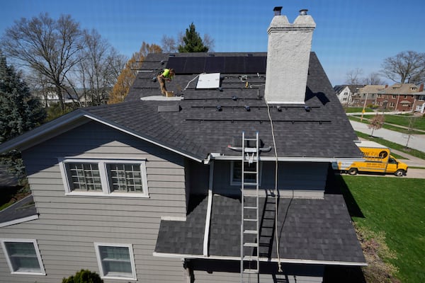 Theodore Tanczuk, of solar installer YellowLite, works to put panels on the roof of a home in Lakewood, Ohio, Wednesday, April 16, 2025. (AP Photo/Sue Ogrocki)