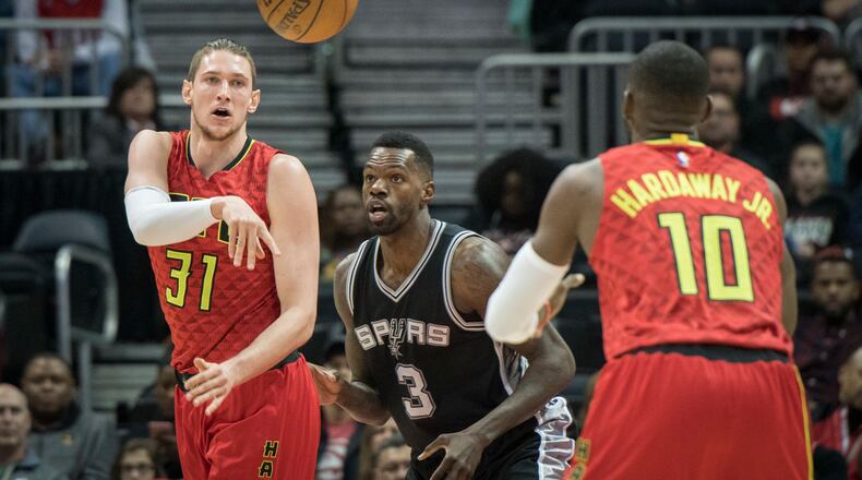 Atlanta Hawks forward Mike Muscala (31) passes to guard Tim Hardaway Jr. (10) as San Antonio Spurs center Dewayne Dedmon (3) defends during the first half of an NBA basketball game, Sunday, Jan. 1, 2017, in Atlanta. (AP Photo/John Amis)