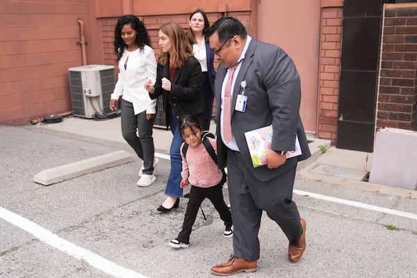 A 4-year-old Mexican girl, who has short bowel syndrome, holds the hand of Yonny Aguilar, a senior paralegal at Public Counsel, as she and her mother, far left, leave a news conference in Los Angeles, Wednesday, May 28, 2025, after their humanitarian parole was terminated and they were ordered to self-deport. (AP Photo/Jae C. Hong)
