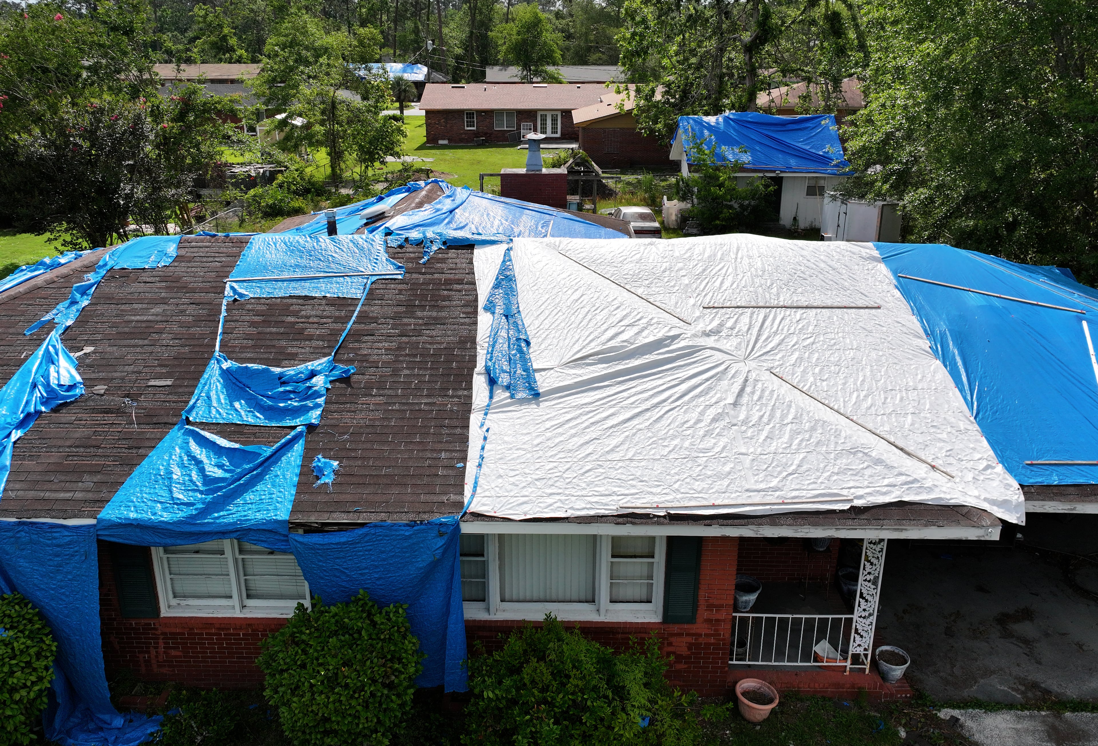 Eight months after Hurricane Helene, tarps still covered many roofs along Barack Obama Boulevard in Valdosta — pictured here on May 27, 2025.  (Hyosub Shin/AJC)