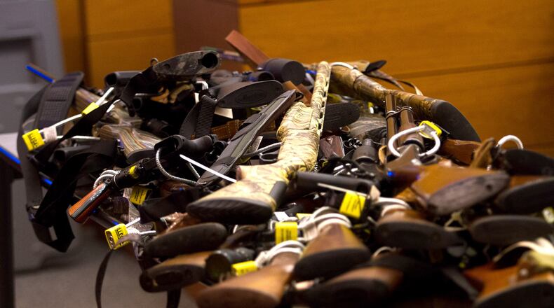 Tex McIver’s dozens of guns are piled onto table in court on Day 12 of McIver’s murder trial. Steve Schaefer / For the AJC