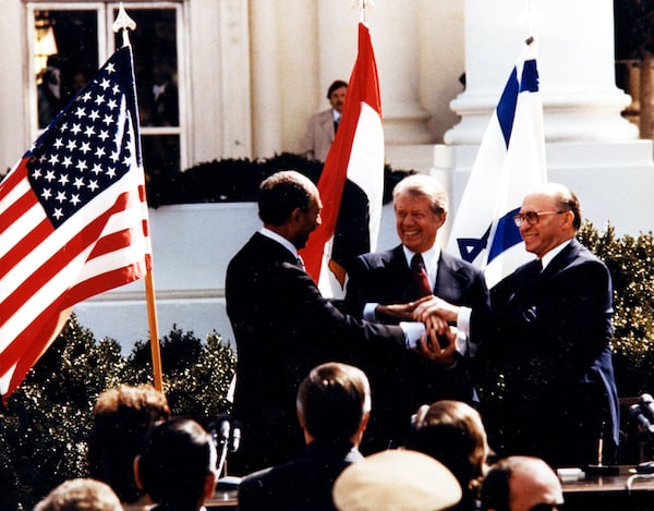 Egyptian President Anwar Sadat (left), President Jimmy Carter (center) and Israeli Prime Minister Menachem Begin clasp hands on the north lawn of the White House in 1979.