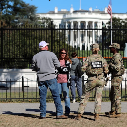 FILE - People talk with National Guard soldiers on the Ellipse, with the White House in the background, Oct. 17, 2025, in Washington. (AP Photo/Rahmat Gul, File)
