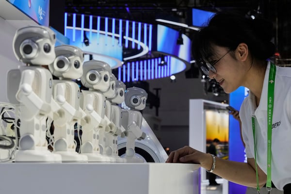 An exhibitor gives a command to a Ubtech humanoid robot at a booth during the 3rd China International Supply Chain Expo at the China International Exhibition Center, in Beijing, China, Friday, July 18, 2025. (AP Photo/Mahesh Kumar A.)
