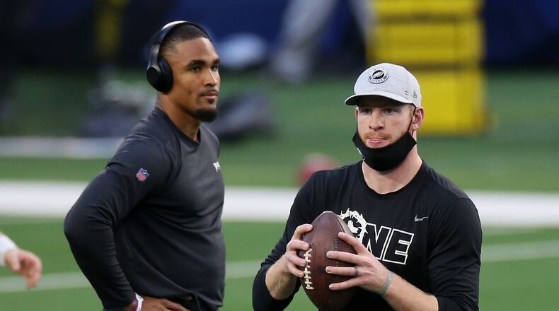 Eagles quarterbacks Jalen Hurts (left) and Carson Wentz warm up before a game against the Dallas Cowboys in December.