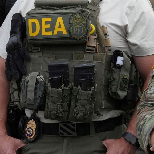 FILE - A Drug Enforcement Administration agent listens as President Donald Trump speaks with members of law enforcement and National Guard soldiers Aug. 21, 2025, in Washington. (AP Photo/Jacquelyn Martin, File)