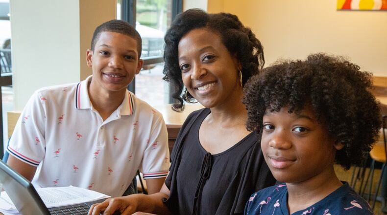 Athara Toussaint (center), searches for her grades online while having breakfast with her sons Dallas (left, age 17) and Julian (14).