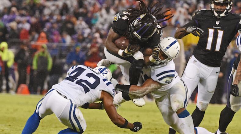 Baltimore Ravens running back Alex Collins, middle, jumps through the Indianapolis Colts' Kenney Moore II (42) and Anthony Walker for a first down in the fourth quarter at M & T Bank Stadium in Baltimore on Saturday, Dec. 23, 207. The Ravens won, 23-16. (Kenneth K. Lam/Baltimore Sun/TNS)