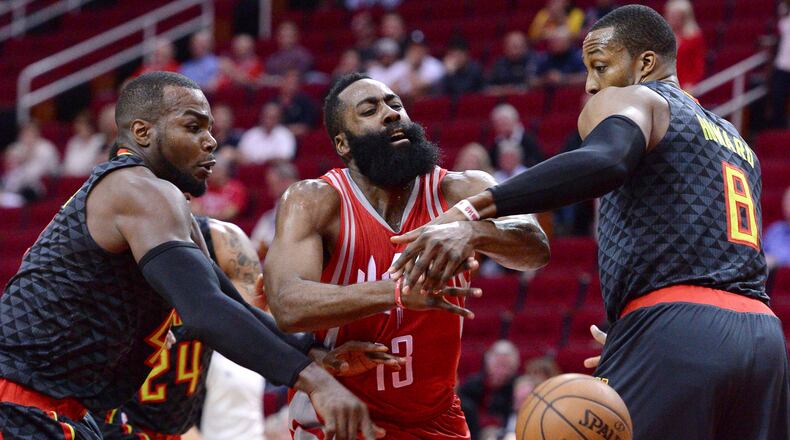 Houston Rockets guard James Harden (13) loses the ball as he drives between Atlanta Hawks forward Paul Millsap, left, and Dwight Howard (8) during the first half of an NBA basketball game Thursday, Feb. 2, 2017, in Houston. (AP Photo/George Bridges)