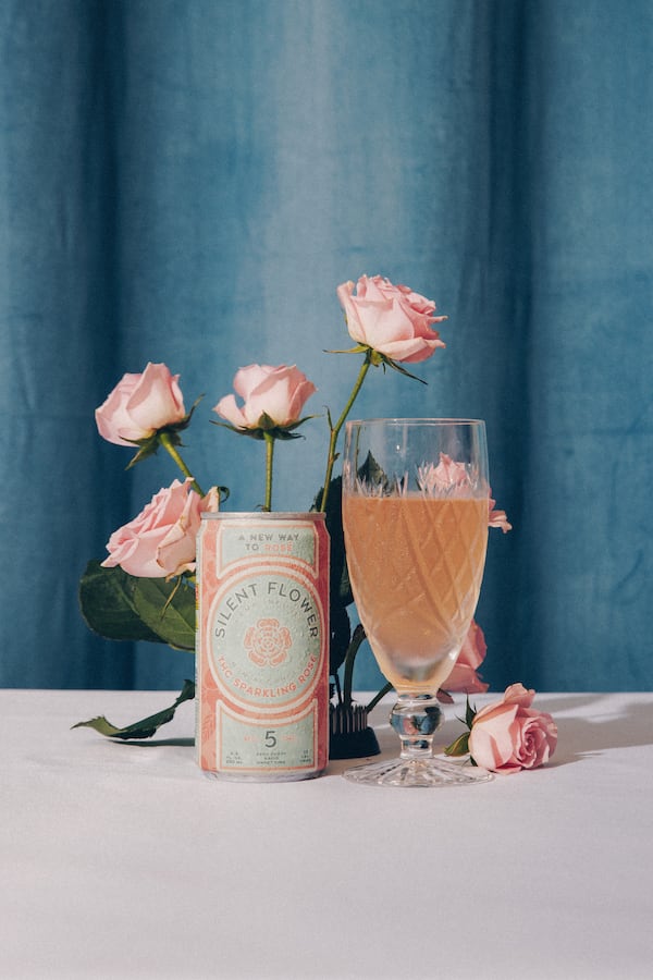 A can of Silent Flower rose sits next to a fancy cut-glass glass filled with the same. Matching roses are arranged behind them.