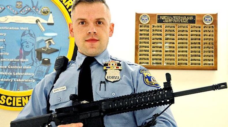Philadelphia police tweeted a photo of Officer Krzyszpof Wrzesinski posing with the weapons, warning parents to "make sure your weapons are secured." (Photo via Philadelphia police)