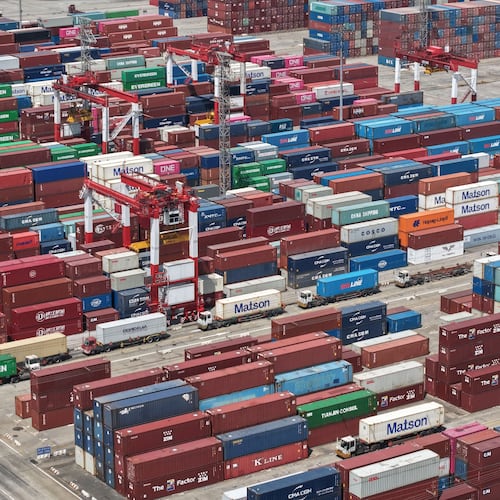 Trucks move past containers stored at a container terminal in Shanghai, China, Tuesday, July 14, 2026. (Chinatopix Via AP)