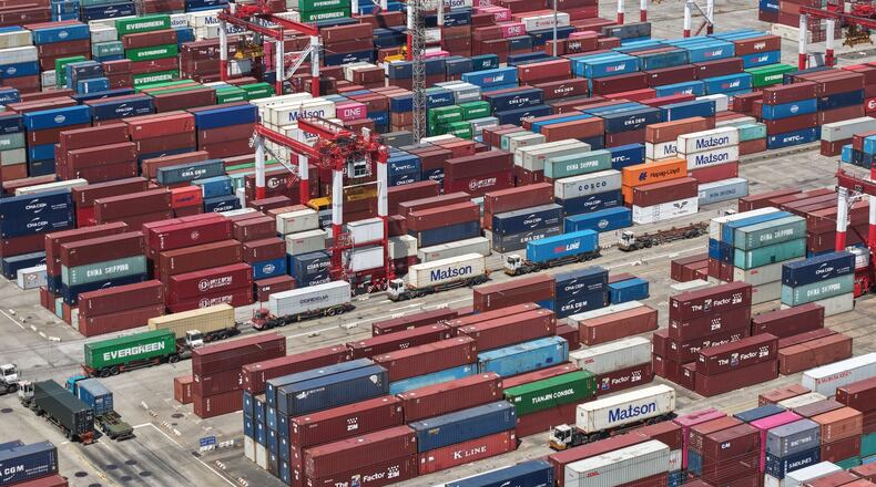 Trucks move past containers stored at a container terminal in Shanghai, China, Tuesday, July 14, 2026. (Chinatopix Via AP)