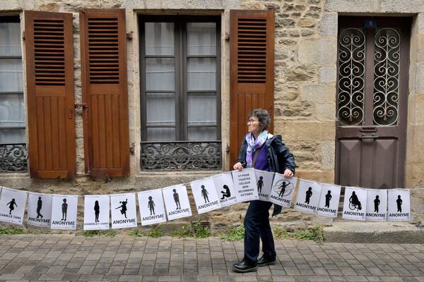 A woman holds a banner representing anonymous victims during a demonstration ahead of the verdict in the trial of Joel Le Scouarnec, a 74-year-old former surgeon, accused of raping and sexually assaulting 299 children, Wednesday, May 28, 2025 in Vannes, Brittany, western France. (AP Photo/Mathieu Pattier)