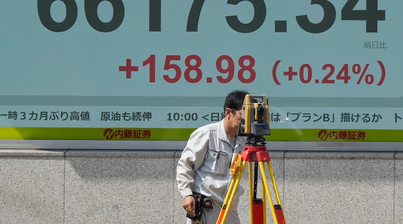 A surveyor works in front of a stock market chart Monday, Aug. 24, 2026 in Tokyo. (AP Photo/Eugene Hoshiko)