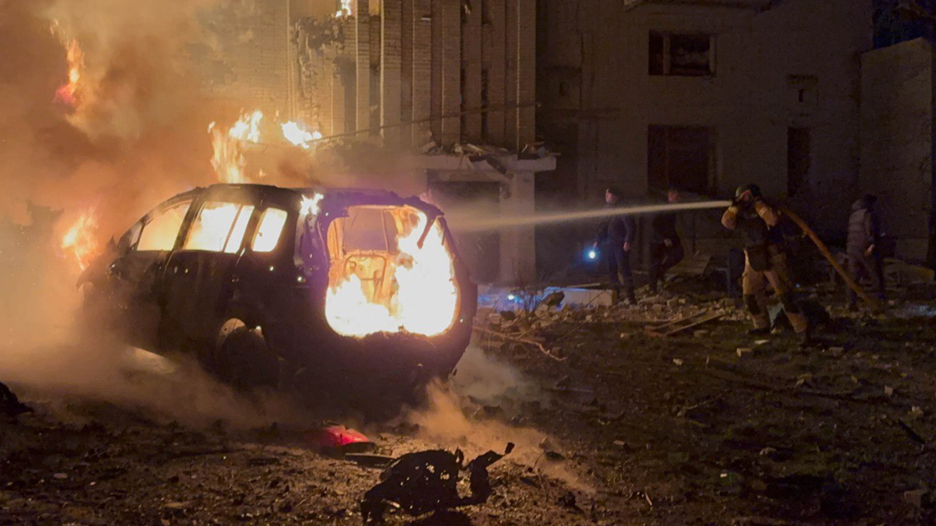In this photo provided by the Ukrainian Emergency Services on Monday, Dec. 8, 2025, a rescue worker puts out a fire of a car in front of a residential building damaged by a Russian strike in Sumy region, Ukraine. (Ukrainian Emergency Service via AP)