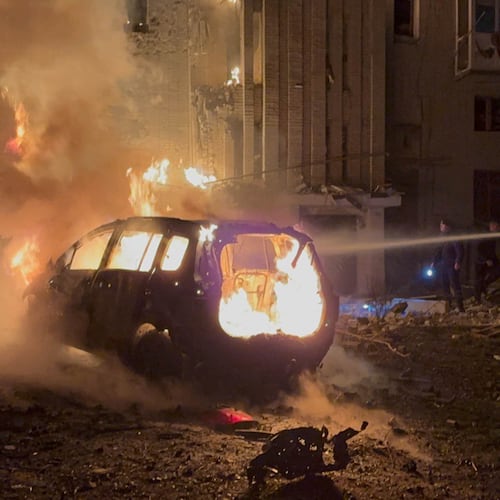 In this photo provided by the Ukrainian Emergency Services on Monday, Dec. 8, 2025, a rescue worker puts out a fire of a car in front of a residential building damaged by a Russian strike in Sumy region, Ukraine. (Ukrainian Emergency Service via AP)