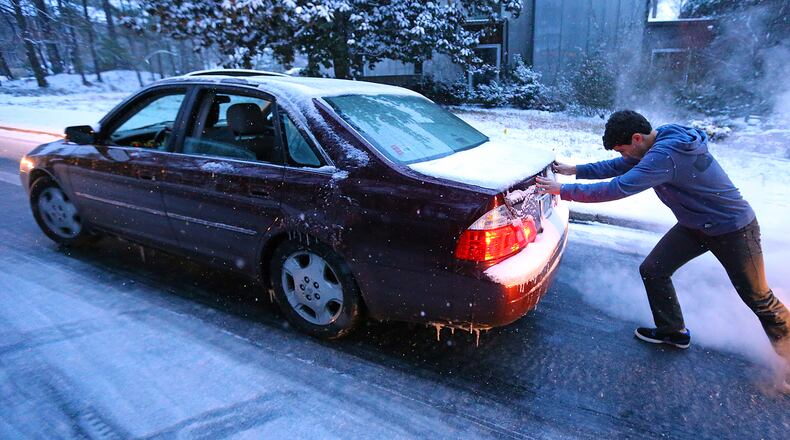 Sammy Rouchdi pushes a stranded motorist, Cameron Scheeler, up an iced-over hill on Womack Road in Dunwoody after he became stuck on the ice trying to get home on Tuesday.