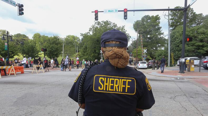 8/15/20 - Stone Mountain, GA - A DeKalb sheriff officer keeps an eye on marchers as several far-right groups, including militias and white supremacists, rally Saturday in the town of Stone Mountain, and a broad coalition of leftist anti-racist groups organized a counter-demonstration there after local authorities closed Stone Mountain park. Jenni Girtman for the Atlanta Journal Constitution