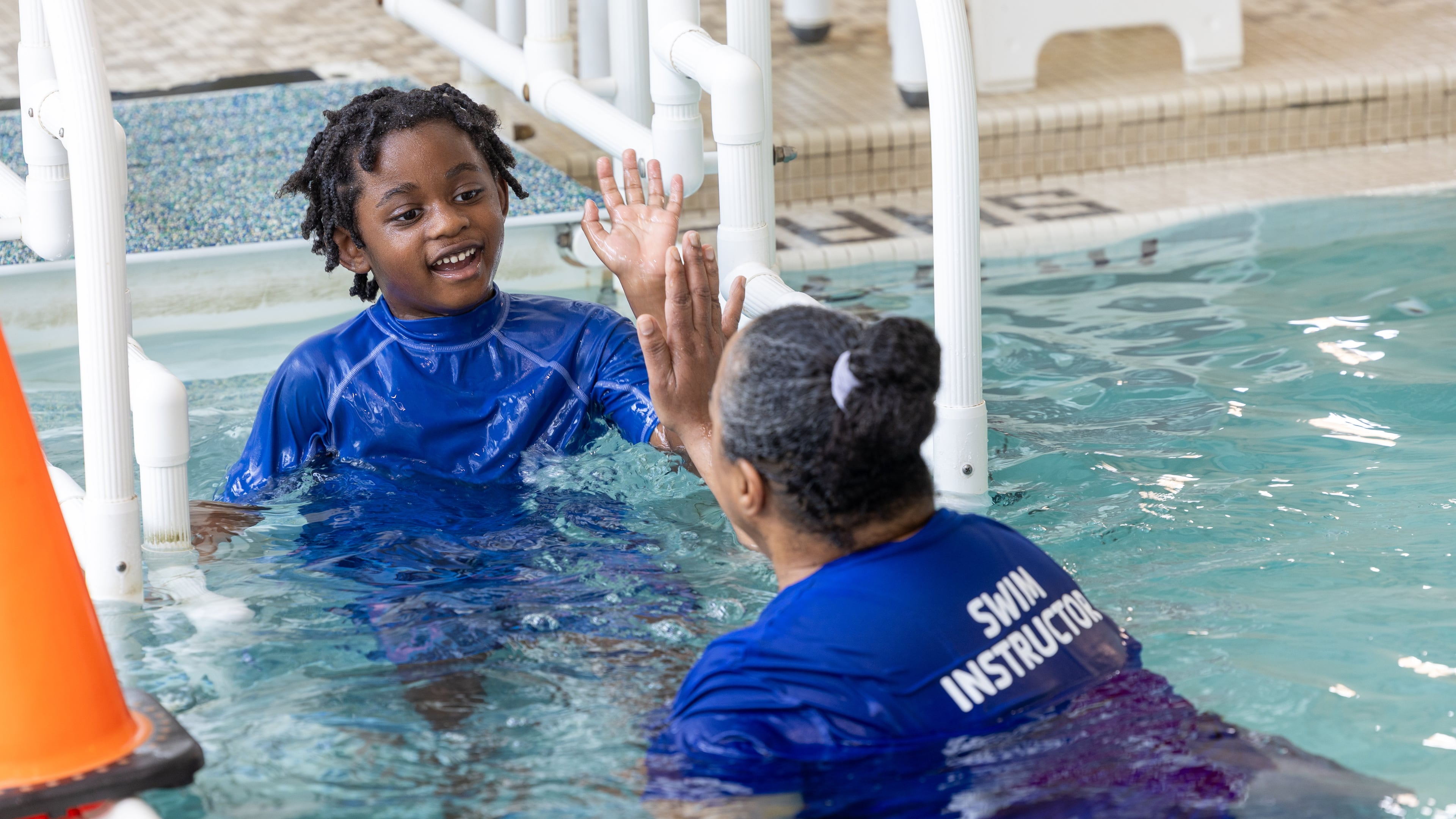 Four-year-old Lewis Davis gets a high-five from his instructor, Lillian Thompson, during an adaptive swim session at the Decatur YMCA earlier this month. (Phil Skinner for the AJC)